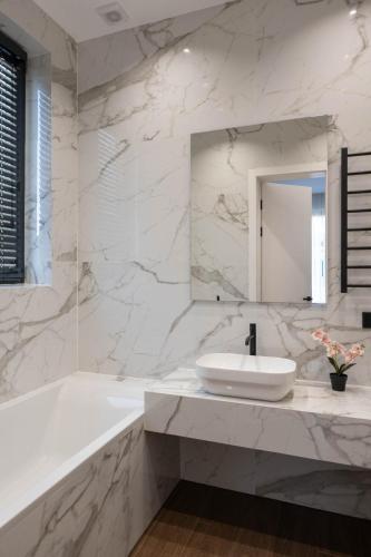 a white bathroom with a tub and a sink at Riviera Zoloche Resort & Spa in Vishenki