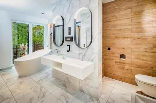 a bathroom with a tub and a sink and mirrors at DAS ERZ Medical Spa & Hotel in Crottendorf