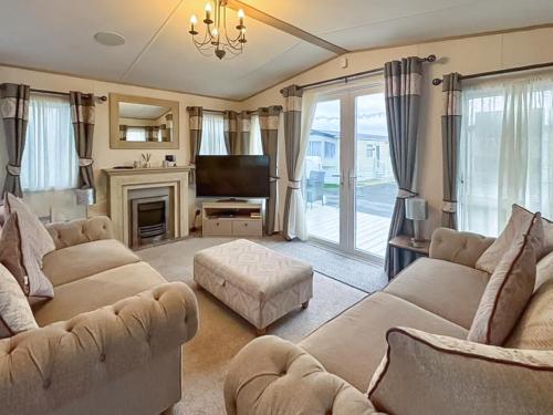 a living room with two couches and a television at Abi Beaumont - Ty Mawr in Rowen