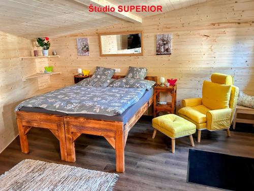 a bedroom with a bed and a yellow chair at MK Apartment Karpaty in Zvončín