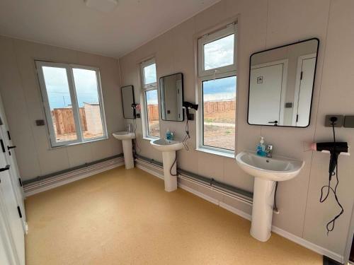 a bathroom with two sinks and two mirrors at Gobi Desert Guesthouse & Tours in Dalandzadgad
