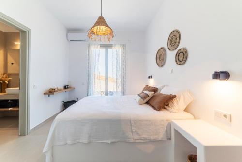 a white bedroom with a bed and a window at Ayelma - Kythnos Villa in Kithnos