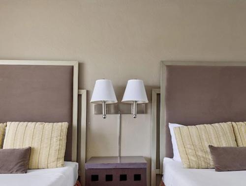 two beds in a hotel room with two lamps at Plantation Hale Suites in Kapaa