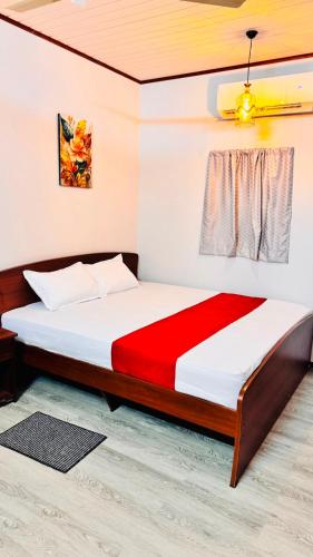 a bedroom with a bed with a red and white comforter at Wonder Stay in Jaffna
