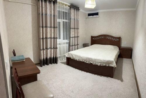 a bedroom with a bed and a desk and a window at NUKUS GUEST HOUSE in Nukus