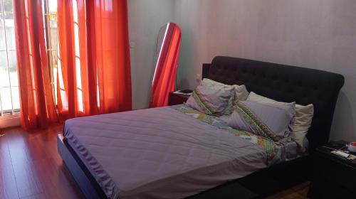a bed in a room with red curtains at Pati place in Mememo