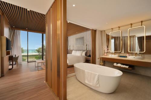 a bathroom with a tub and a bedroom with a bed at Aqua Vista Hoi An Beachfront Villas in Hoi An