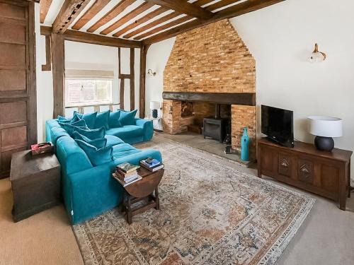 a living room with a blue couch and a fireplace at The Cottage in Chelsworth