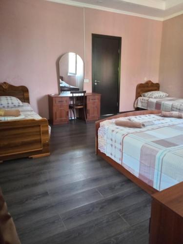 a bedroom with two beds and a desk and a mirror at Guest house Gio in Kobuleti