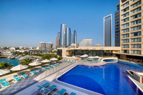 a pool with chairs and umbrellas in a hotel at InterContinental Abu Dhabi by IHG in Abu Dhabi