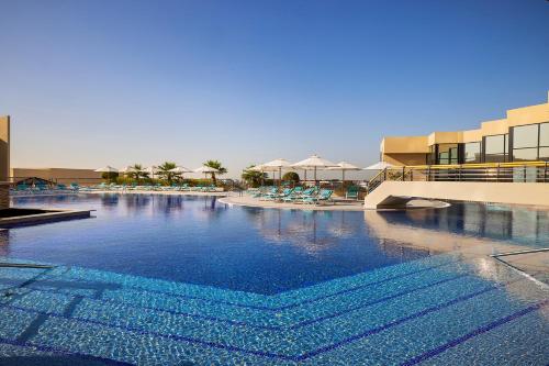 a large swimming pool in a resort with chairs and umbrellas at InterContinental Abu Dhabi by IHG in Abu Dhabi