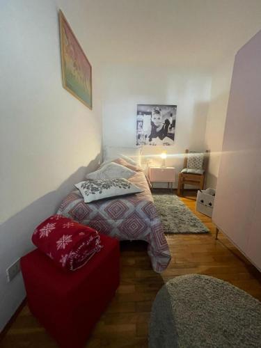 a bedroom with a bed and a red ottoman at A Casa di Zio Zeffy in Châtillon