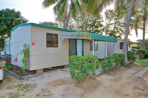 a small white house with trees in front of it at Alva Beach Tourist Park in Alva