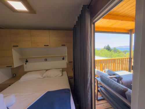 a bedroom with a bed and a balcony at Mobile homes Camp Kozica in Sibinj Krmpotski