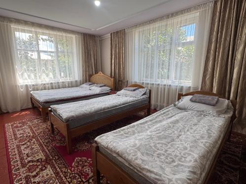 a room with three beds and two windows at Meerim Guest House in Bokonbayevo