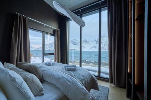 a bedroom with a bed with a view of the ocean at Fredvang Lodge, Lofoten in Fredvang