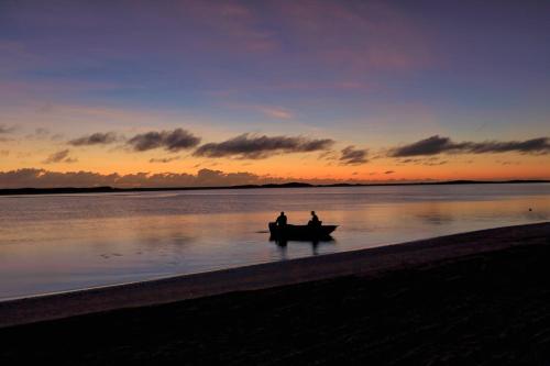 two people in a boat on the beach at sunset at Alva Beach Tourist Park in Alva
