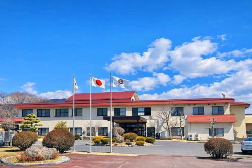 a building with two flags in front of it at Nunohiki Onsen Komoro in Komoro