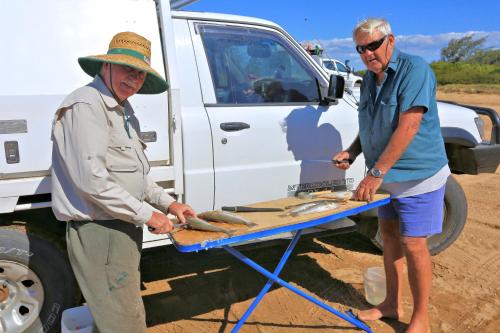 two men standing next to a table in front of a truck at Alva Beach Tourist Park in Alva