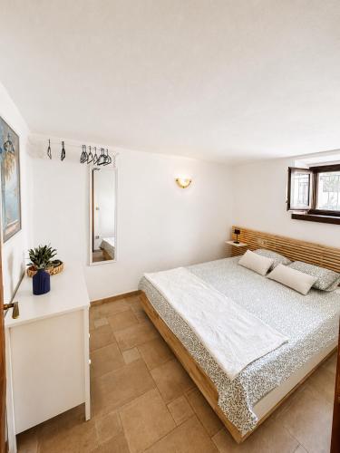 a white bedroom with a bed and a mirror at Biba Holiday in Omišalj