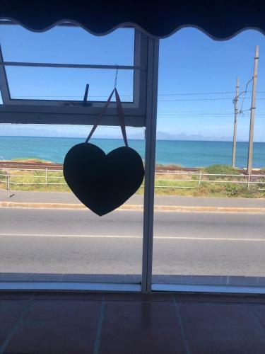 a heart hanging from a window with a view of the ocean at Caradoc House in Muizenberg