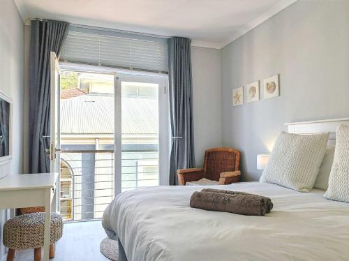 a bedroom with a bed and a large window at Waveside Stays in Muizenberg