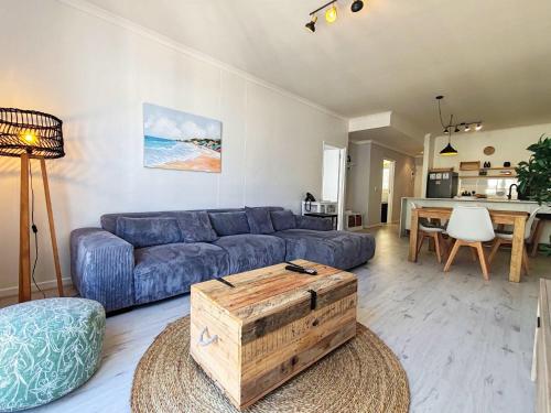 a living room with a blue couch and a table at Waveside Stays in Muizenberg