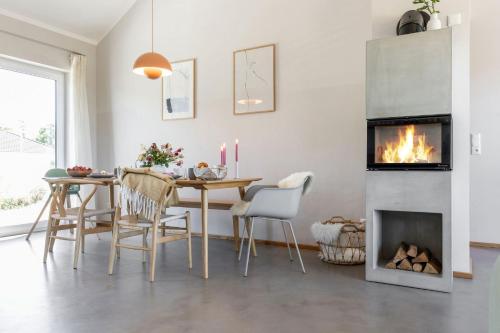 a dining room with a table and a fireplace at Feldkoje - Luxuriöses Design-Ferienhaus mit Kamin und Feldrandlage in Fehmarn