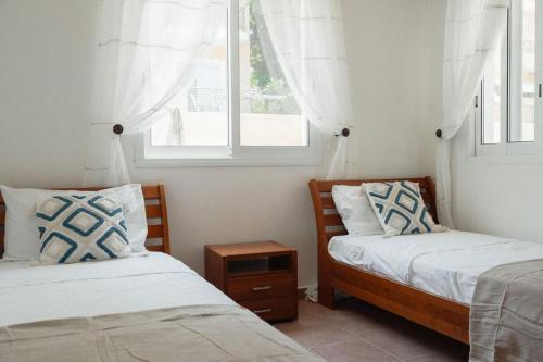 two beds in a room with two windows at Chloraka Sea View Apt with Pool in Khlorakas
