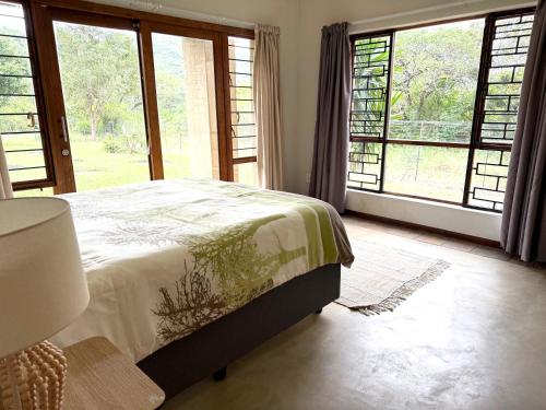 a bedroom with a bed and large windows at The Sanctuary- Self Catering Accommodation in Nelspruit