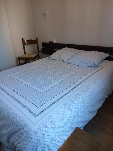 a bed with a blue comforter on top of it at Hôtel de Cenves in Cenves