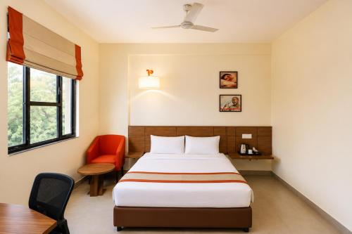 ein Schlafzimmer mit einem Bett, einem Schreibtisch und einem Stuhl in der Unterkunft Max Hotels Jabalpur in Jabalpur