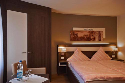 a bedroom with a bed and a table with a bottle of water at Hotel Gasthaus Huwer in Bernkastel-Kues