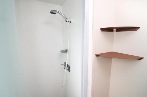 a shower in a bathroom with a white wall at Camping Héiltzerstee in Rambrouch