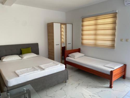 a bedroom with two beds and a window with blinds at Apartmani Ličina in Bečići