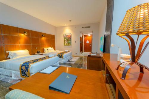 a hotel room with two beds and a desk at Wings by Croske Resort Langkawi in Pantai Cenang