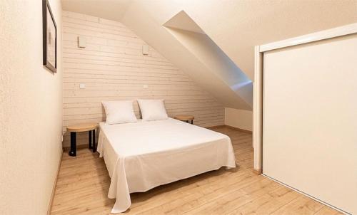 a bedroom with a white bed in a attic at Résidence Vacancéole Les Chalets d'Ax in Ax-les-Thermes