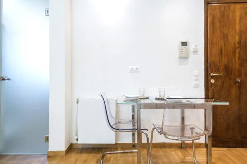 a glass table and two chairs in a room at Syntagma Gem 1 in Athens