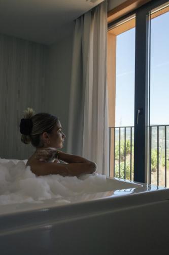 a woman sitting in a bath tub with a window at Quinta do Roso - Douro Wine Estate - by FERO in Lamego