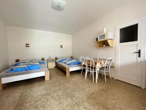 a room with two beds and a table and chairs at Ubytovanie Klára in Veľký Meder