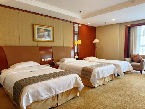 a hotel room with three beds and a couch at Beijing Jiangsu Plaza Hotel in Beijing