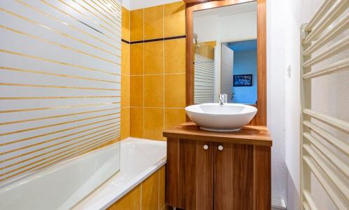 a bathroom with a sink and a tub at Résidence Vacancéole Les Chalets d'Ax in Ax-les-Thermes