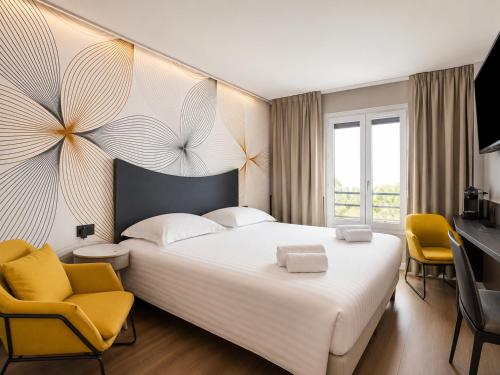a bedroom with a large white bed and two yellow chairs at Logis Hotel Center in Brest