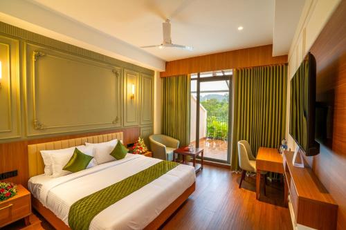 a bedroom with a bed and a desk and a television at HOTEL MARIAPARK KALLooRKKAD in Vāzhākulam
