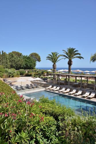 a swimming pool with chaise lounge chairs and palm trees at La Réserve Esterel in Saint-Raphaël
