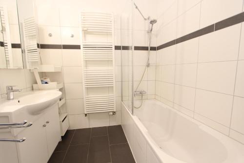 a white bathroom with a tub and a sink at Langeoog entspannt in Langeoog