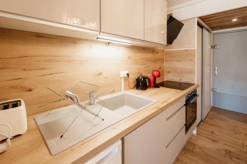 a kitchen with a white sink and wooden walls at Le Nid Cozy - Appart avec Piscine, Terrain de Tenis et Balcon in Métabief