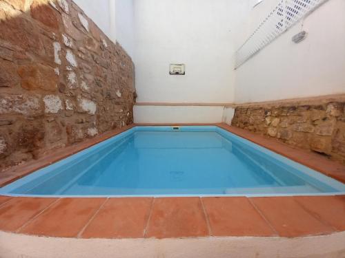 a large blue pool in a room with a stone wall at La Casa del Abuelo Curro in Baños de la Encina