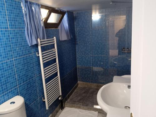 a blue tiled bathroom with a toilet and a sink at Xenonas ΚITHΑIRON in Vília