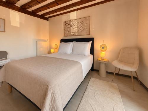a bedroom with a large bed and a chair at Maison HELIOS - Eguisheim in Eguisheim